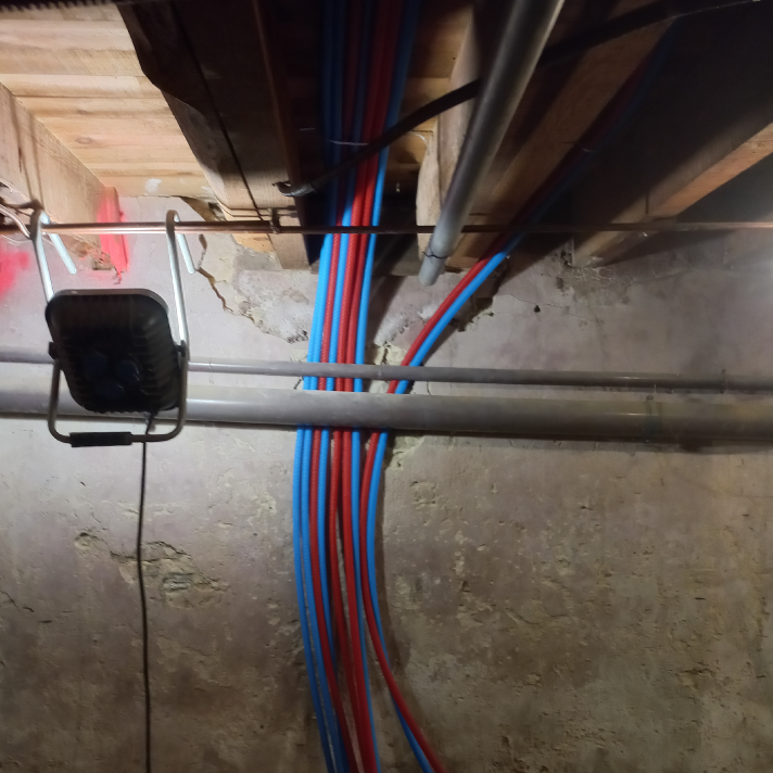 Fixation de tuyaux d'alimentation en eau PER rouge et bleu sous plafond à Yzosse par l'artisan plombier LIMA.