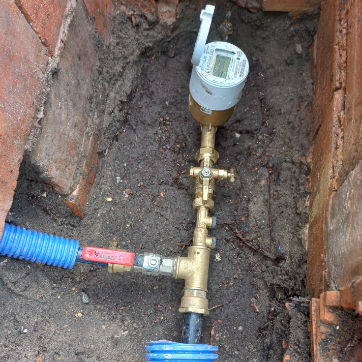 Pose et raccordement en laiton d'un nouveau compteur d'eau dans un regard extérieur à Hinx par le plombier LIMA.