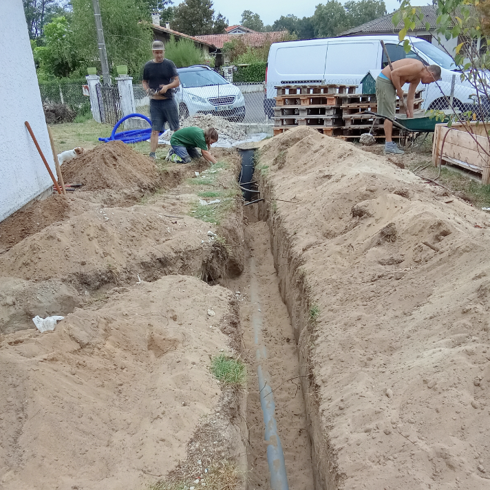 Pose minutieuse de canalisations d'assainissement en tranchée par l'équipe de plombiers LIMA lors de travaux de construction à Dax.
