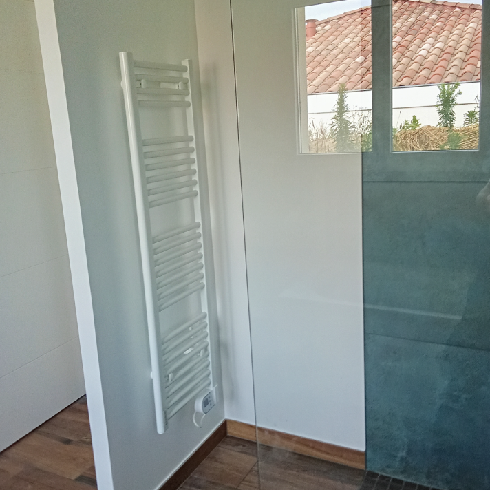 Pose d'un sèche-serviette blanc et d'une paroi de douche en verre sur mesure à Saint-Paul-lès-Dax par LIMA Plomberie.