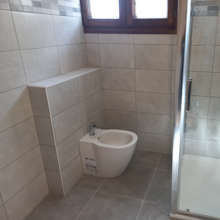 Pose d'un bidet au sol moderne et habillage mural en carrelage gris lors d'une rénovation sanitaire à Dax, dans les Landes par le plombier LIMA.