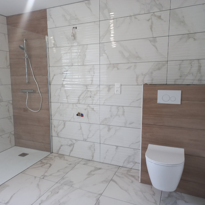 Pose d'un WC suspendu moderne avec habillage mural effet bois lors d'une rénovation sanitaire à Narrosse par le plombier LIMA.